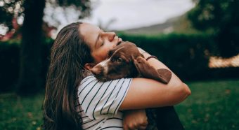 Natural lifestyle, zen lifestyle, woman in white and black stripe shirt hugging brown short coated dog